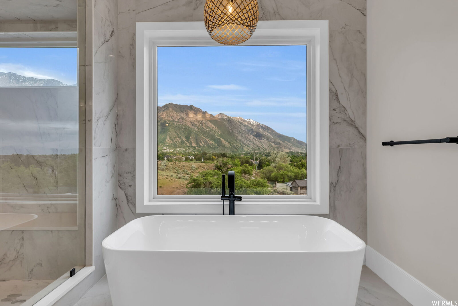 Primary bath with freestanding tub under a mountain-view window